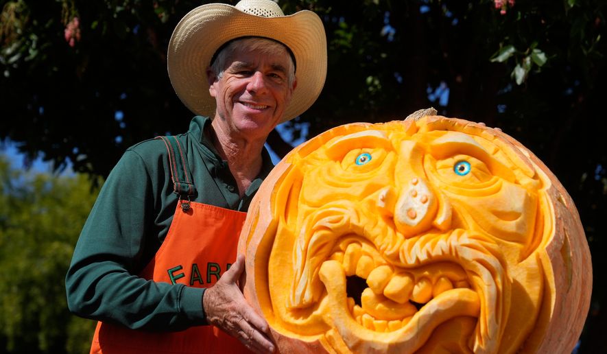 Farmer Mike Valladao poses next to a pumpkin he carved at the Safeway World Championship Pumpkin Weigh-Off, Monday, Oct. 12, 2026, in Half Moon Bay, Calif. (AP Photo/Jeff Chiu)
