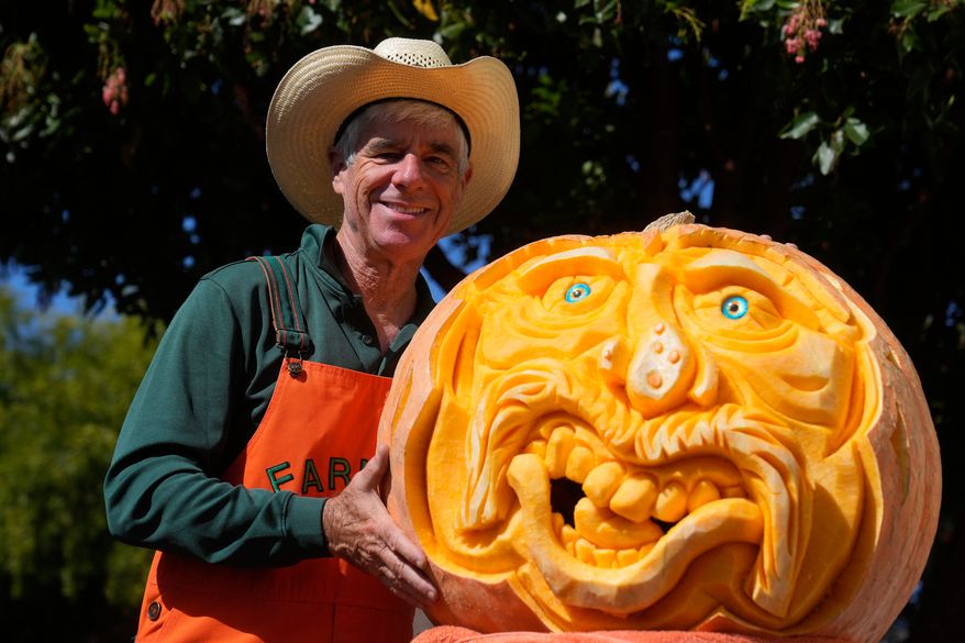 Farmer Mike Valladao poses next to a pumpkin he carved at the Safeway World Championship Pumpkin Weigh-Off, Monday, Oct. 12, 2026, in Half Moon Bay, Calif. (AP Photo/Jeff Chiu)