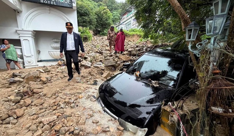 In this image from a video released by Phuket province's Public Relations Department, an official walks at the site of a mudslide after flash flooding in Phuket, Thailand, Monday, Oct. 26, 2026. (Phuket province's Public Relations Department via AP)
