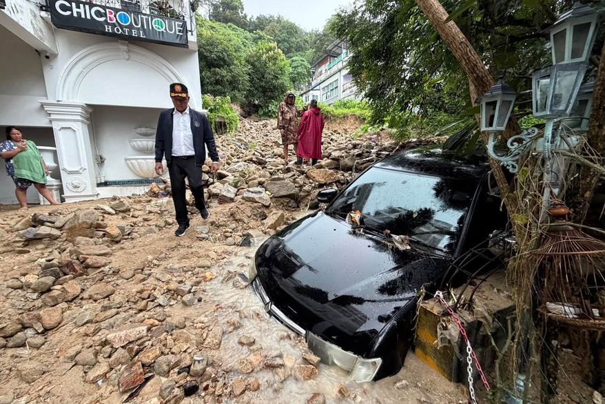 In this image from a video released by Phuket province's Public Relations Department, an official walks at the site of a mudslide after flash flooding in Phuket, Thailand, Monday, Oct. 26, 2026. (Phuket province's Public Relations Department via AP)