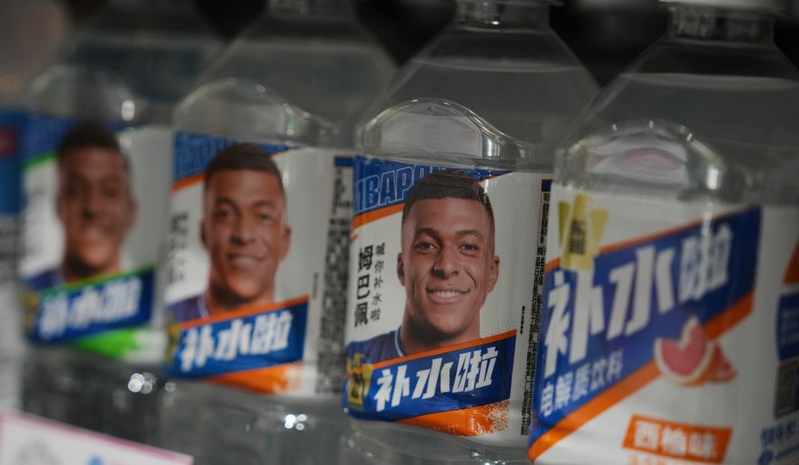 Bottles of electrolyte drink by Dongpeng Beverage Group featuring images of French soccer star Kylian Mbappé are displayed for sale at a supermarket in Beijing, Tuesday, Oct. 27, 2026. (AP Photo/Andy Wong)