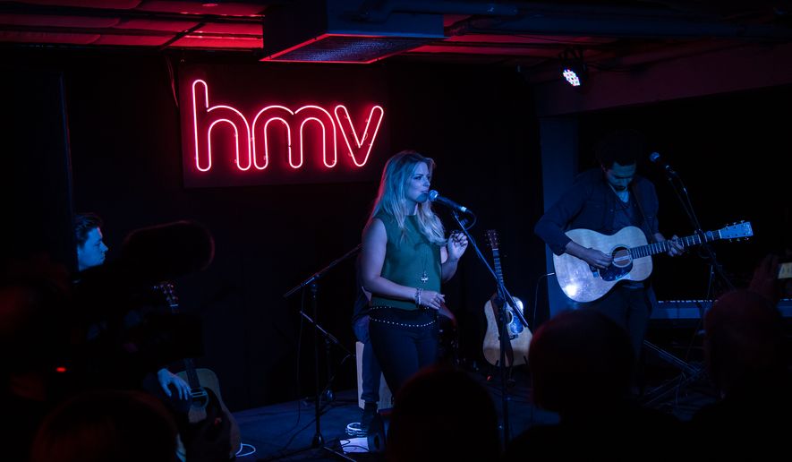 Musicians Crissie Rhodes, center and Ben Earle, right, of The Shires performs on stage at the Oxford Street HMV store, in London, Wednesday, Oct. 5, 2016. (Photo by Vianney Le Caer/Invision/AP)