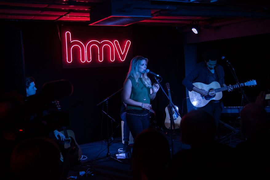 Musicians Crissie Rhodes, center and Ben Earle, right, of The Shires performs on stage at the Oxford Street HMV store, in London, Wednesday, Oct. 5, 2016. (Photo by Vianney Le Caer/Invision/AP)