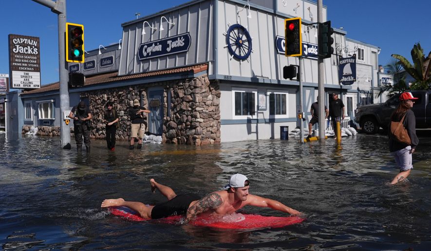 A man surfs through floodwaters in Huntington Beach, Calif., Wednesday, Oct. 28, 2026. (AP Photo/Jae C. Hong)