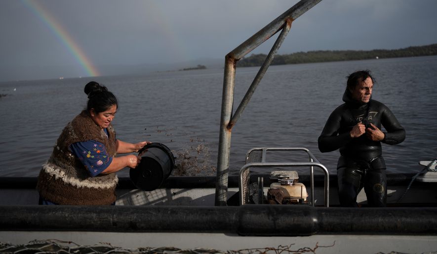 Yesica Fabiana Leviñanco, left, and her partner, Paulo Vera Perez, prepare for a fishing journey in Repollal, in the Guaitecas Archipelago, Chile, Wednesday, May 21, 2025. (AP Photo/Adriana Thomasa)