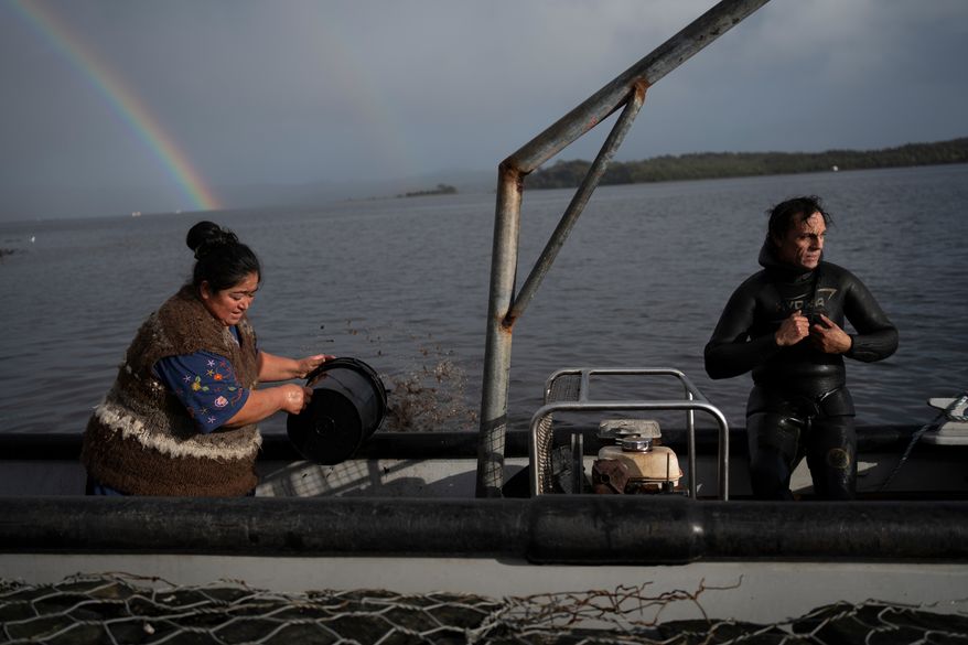 Yesica Fabiana Leviñanco, left, and her partner, Paulo Vera Perez, prepare for a fishing journey in Repollal, in the Guaitecas Archipelago, Chile, Wednesday, May 21, 2025. (AP Photo/Adriana Thomasa)