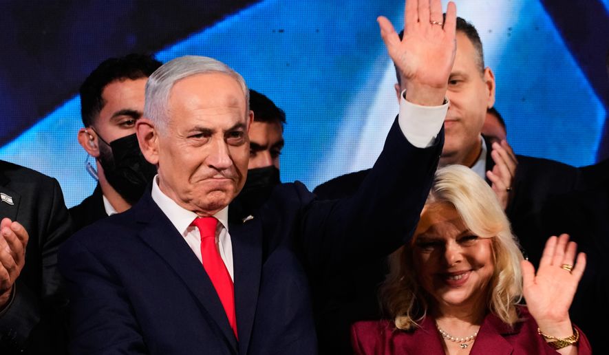 Israeli Prime Minister Benjamin Netanyahu, accompanied by his wife, Sara, waves to supporters at Likud party headquarters in Jerusalem after the release of the first exit poll results in Israel's general election, Wednesday, Oct. 28, 2026. (AP Photo/Ohad Zwigenberg)
