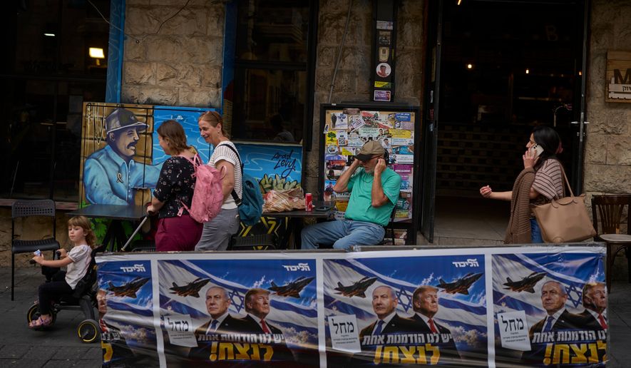 People walk next to a Likud party campaign ad featuring Israeli Prime Minister Benjamin Netanyahu and U.S. President Donald Trump, with a Hebrew message reading "We have one opportunity to win," in Jerusalem on Wednesday, Oct. 28, 2026, a day after the elections in Israel. (AP Photo/Ohad Zwigenberg)