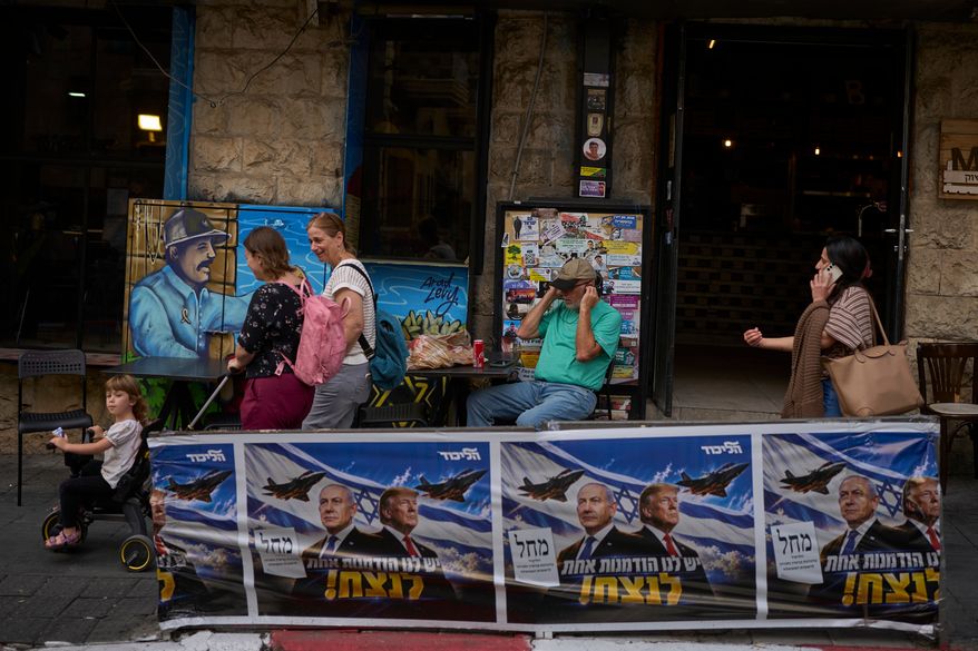 People walk next to a Likud party campaign ad featuring Israeli Prime Minister Benjamin Netanyahu and U.S. President Donald Trump, with a Hebrew message reading "We have one opportunity to win," in Jerusalem on Wednesday, Oct. 28, 2026, a day after the elections in Israel. (AP Photo/Ohad Zwigenberg)