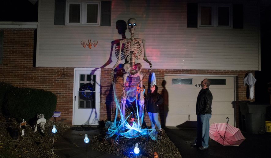 Chrissy and Dominic Montesano look at the 12-foot tall skeleton in front of their home in Valencia, Pennsylvania, October 15, 2020. (AP Photo/Ted Shaffrey, File)