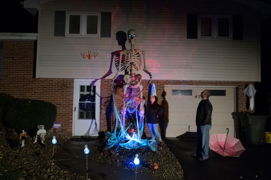 Chrissy and Dominic Montesano look at the 12-foot tall skeleton in front of their home in Valencia, Pennsylvania, October 15, 2020. (AP Photo/Ted Shaffrey, File)