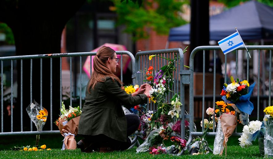 FILE - A woman places a bouquet of flowers at a makeshift memorial for victims of an attack outside of the Boulder County, Colo., courthouse, June 3, 2025, in Boulder, Colo. (AP Photo/David Zalubowski, File)