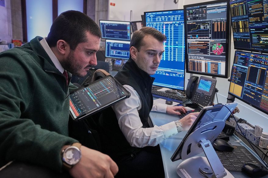 Traders Drew Cohen, left, and Dylan Halvorsan work on the floor of the New York Stock Exchange, Monday, Jan. 26, 2026. (AP Photo/Richard Drew, File)