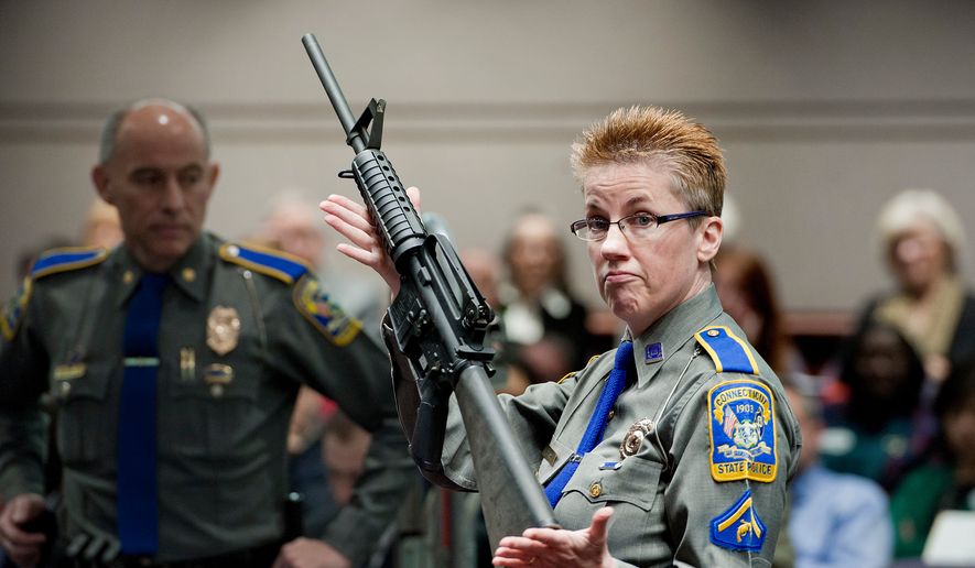 Firearms training unit Detective Barbara J. Mattson, of the Connecticut State Police, holds up a Bushmaster AR-15 rifle, the same make and model of gun used by Adam Lanza in the Sandy Hook School shooting, for a demonstration during a hearing of a legislative subcommittee reviewing gun laws, Jan. 28, 2013, at the Legislative Office Building in Hartford, Conn. (AP Photo/Jessica Hill, File)