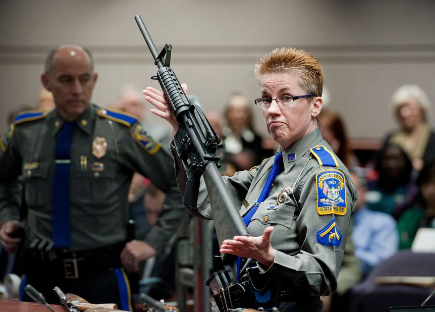 Firearms training unit Detective Barbara J. Mattson, of the Connecticut State Police, holds up a Bushmaster AR-15 rifle, the same make and model of gun used by Adam Lanza in the Sandy Hook School shooting, for a demonstration during a hearing of a legislative subcommittee reviewing gun laws, Jan. 28, 2013, at the Legislative Office Building in Hartford, Conn. (AP Photo/Jessica Hill, File)