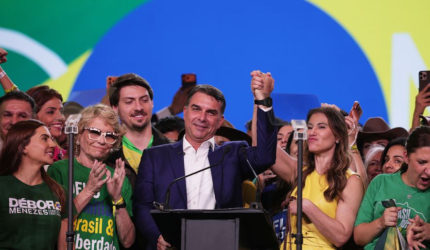 Brazilian Sen. Flavio Bolsonaro, flanked by his mother Rogéria Bolsonaro, second left, and wife Fernanda, acknowledges supporters during the Liberal Party convention where he was confirmed as the party's presidential candidate,in Sao Paulo, Saturday, July 25, 2026. (AP Photo/Ettore Chiereguini)