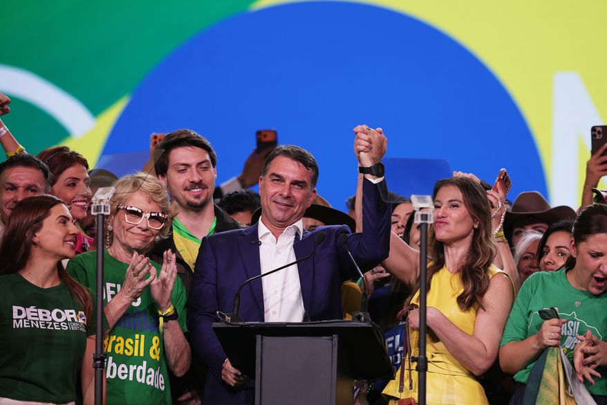 Brazilian Sen. Flavio Bolsonaro, flanked by his mother Rogéria Bolsonaro, second left, and wife Fernanda, acknowledges supporters during the Liberal Party convention where he was confirmed as the party's presidential candidate,in Sao Paulo, Saturday, July 25, 2026. (AP Photo/Ettore Chiereguini)