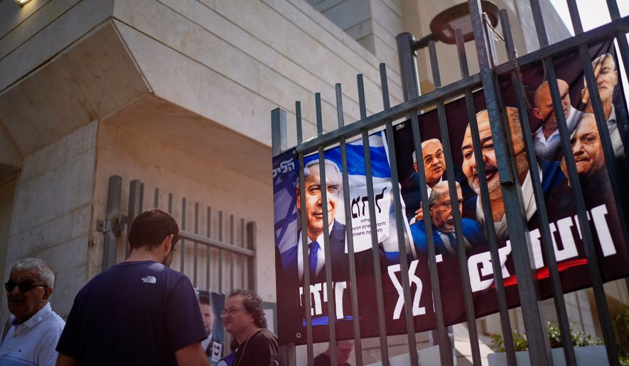 People gather outside a polling station beside campaign posters, including one depicting Benjamin Netanyahu, during Israel's general election in Tel Aviv, Israel, Tuesday, Oct. 27, 2026. (AP Photo/David Goldman)
