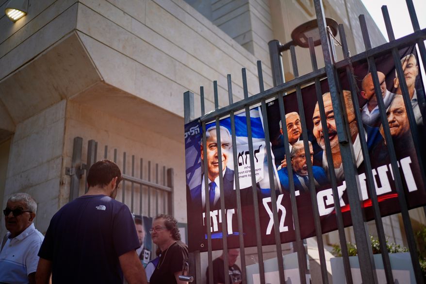 People gather outside a polling station beside campaign posters, including one depicting Benjamin Netanyahu, during Israel's general election in Tel Aviv, Israel, Tuesday, Oct. 27, 2026. (AP Photo/David Goldman)