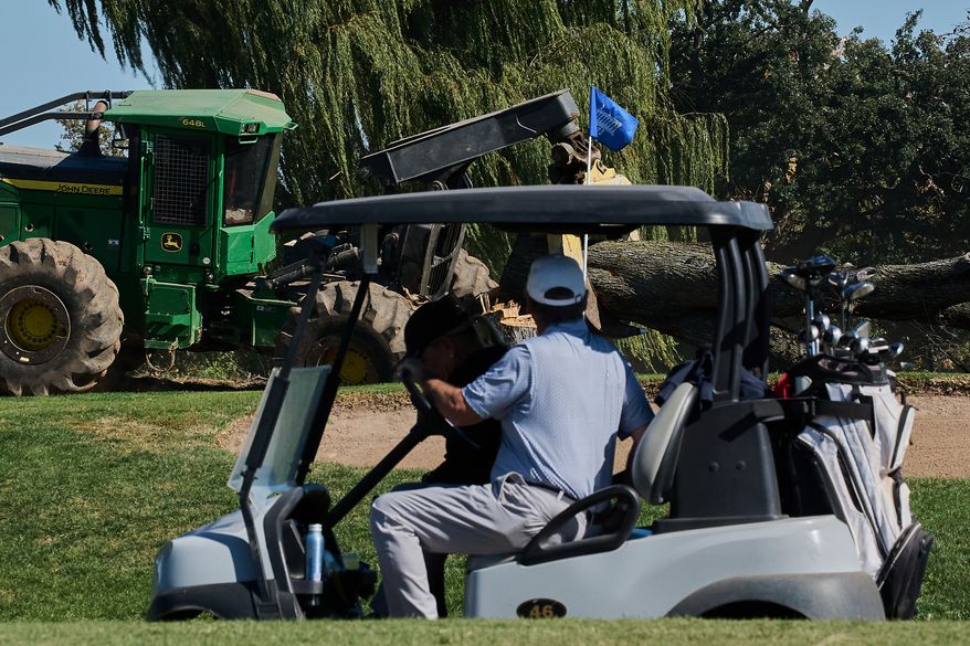People drive a golf cart past ongoing tree removal at East Potomac Park Golf Course, Monday, Oct. 26, 2026, in Washington. (AP Photo/Julia Demaree Nikhinson)