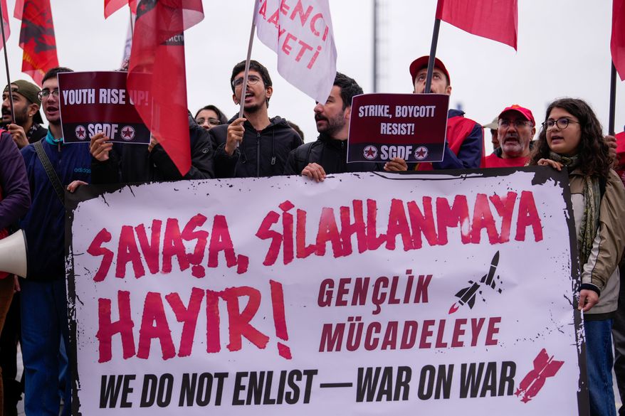 People shout slogans during a protest outside Haydarpasa port calling for the end of shipments to Israel, in Istanbul, Turkey, Friday, Oct. 30, 2026. The banner reads in Turkish: "No to war, no to armament!". (AP Photo/Emrah Gurel)