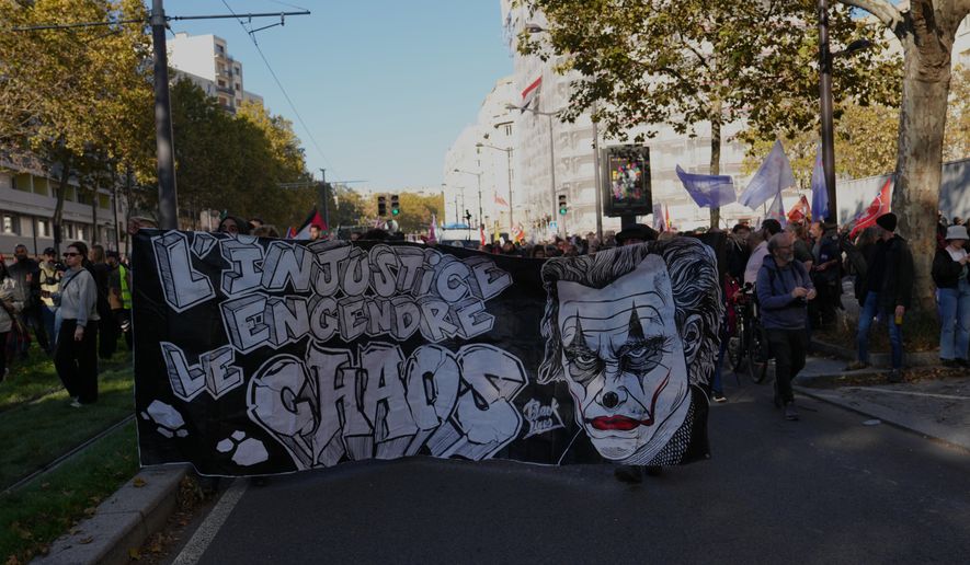 Demonstrators hold a banner reading: "Injustice brings chaos" as they gather before a demonstration against rising living costs in Paris, Saturday, Oct. 31, 2026. (AP Photo/Aurelien Morissard)