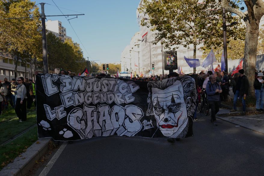 Demonstrators hold a banner reading: "Injustice brings chaos" as they gather before a demonstration against rising living costs in Paris, Saturday, Oct. 31, 2026. (AP Photo/Aurelien Morissard)